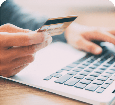 Person holding credit card near laptop.